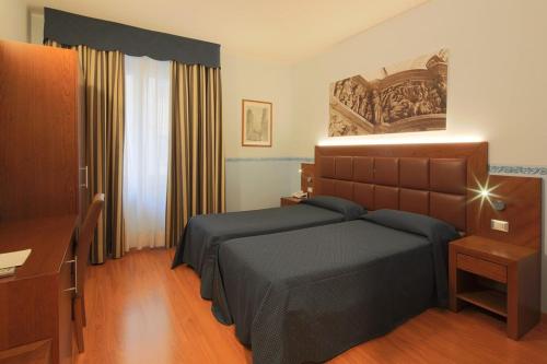 a bedroom with a bed and a desk and a window at Hotel Terminus & Plaza in Pisa