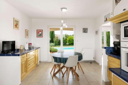 une cuisine avec une table et des chaises dans une cuisine dans l'établissement Villa La Cavayere swimming pool air conditioning, à Carcassonne