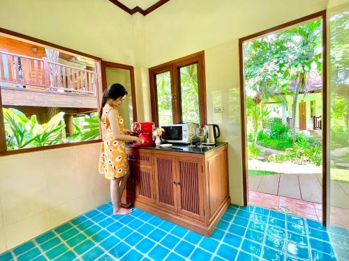 a woman standing in a kitchen with a coffee pot at Oriental Siam Resort - SHA Extra Plus Certified in Chiang Mai