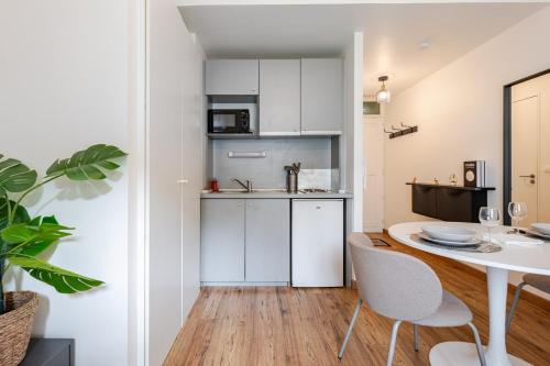 une cuisine avec des armoires blanches et une table et des chaises dans l'établissement Bright Central Studio Evry- 20 min from Paris, Évry-Courcouronnes