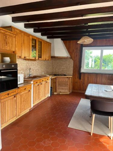 une cuisine avec des armoires en bois, une table et une fenêtre dans l'établissement Les Combres, à La Daguenière