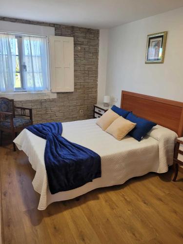 a bedroom with a large bed with blue pillows at GRUPO GONTAD CASA CARMUCHA in Graña