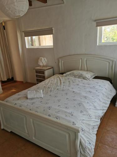 a bedroom with a white bed with a white comforter at Casa da Abelha- Beehouse in Romão