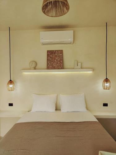a bedroom with a bed with two pillows and two lights at Macarena Paredon in El Paredón Buena Vista