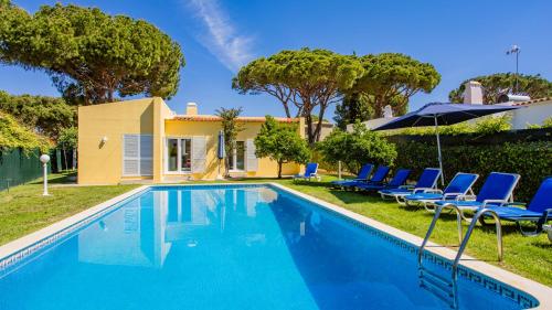 a swimming pool with chairs and a house at Villa Girassol in Vilamoura