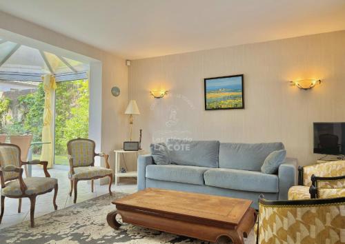 un salon avec un canapé bleu et des chaises dans l'établissement Maison de famille L'Amandoise, à Le Touquet-Paris-Plage