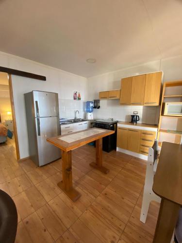 a kitchen with a wooden table and a refrigerator at Loft Tongoy 1 frente al mar in Coquimbo
