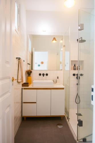 a white bathroom with a sink and a shower at Artist's Retreat near the Riverside with AC in Lisbon