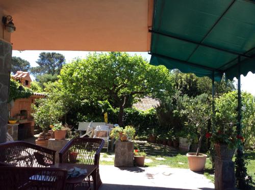 a patio with a table and a green umbrella at Villa Nanda a 15 minuti da Roma piscina esclusiva , villa nella natura in Formello