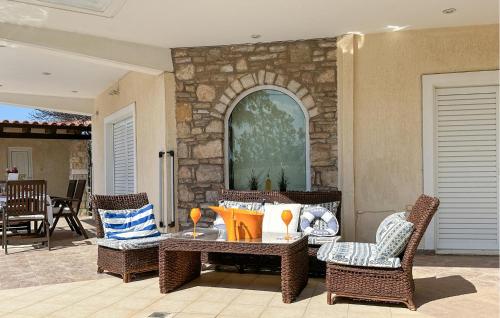 a patio with a table and chairs and a stone wall at Gorgeous Home In Lagonisi With Wifi in Lagonissi