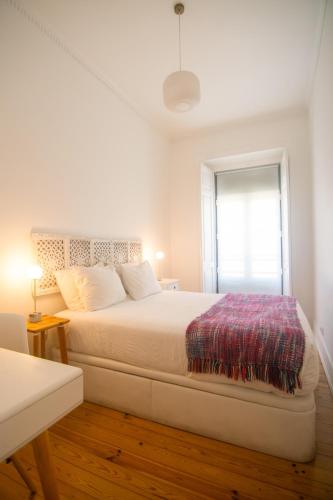 a white bedroom with a large bed and a window at Artist's Retreat near the Riverside with AC in Lisbon