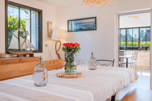 une salle à manger avec une table et des roses rouges dans un vase dans l'établissement Villa Atlantique, à Le Touquet-Paris-Plage