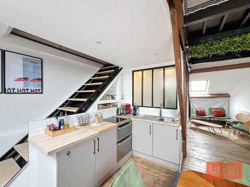 une cuisine avec des placards blancs et un escalier en colimaçon dans l'établissement La passerelle, duplex atypique de charme, à Wimereux