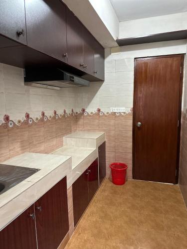 a kitchen with brown cabinets and a red trash can at Baridhara Sweet Home in Dhaka