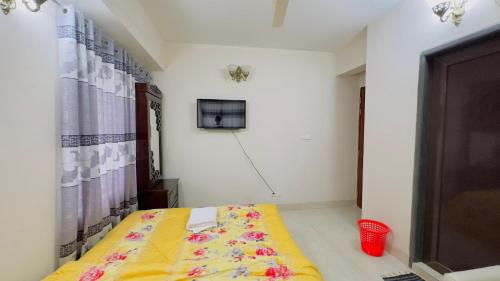 a room with a bed with a yellow blanket at Baridhara Sweet Home in Dhaka