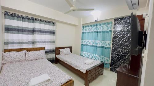 a bedroom with two beds and a flat screen tv at Baridhara Sweet Home in Dhaka