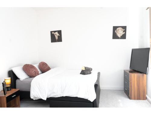a bedroom with a bed and a tv in it at Spacious Pad - Long Stays & Contractors - Close to Sports Village, Leigh Market, & Mesnes Park - Easy Parking - Speedy Wi-Fi in Leigh