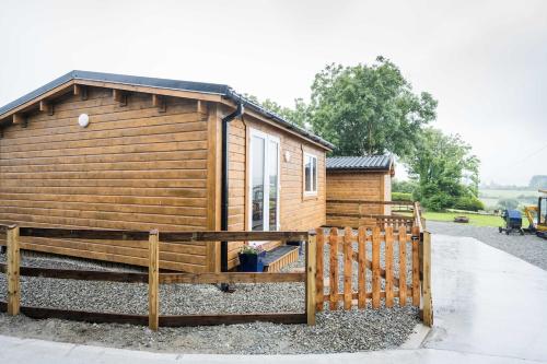 a wooden cabin with a fence in front of it at The Stall at CasaClarig - West Cork Cabin with Sauna in Ballydehob