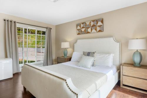a bedroom with a white bed and a window at Grapevine by AvantStay Secluded 5BR Villa 4 Acres of Vineyards Avo Groves in Temecula