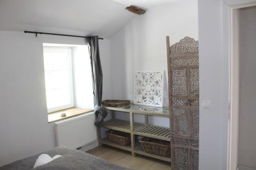 1 dormitorio con cama, ventana y estante en Le Néblon insolite, en Ouffet