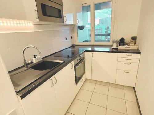 une cuisine blanche avec un évier et un micro-ondes dans l'établissement Studio Cosy Au Centre d'Evry, Évry-Courcouronnes