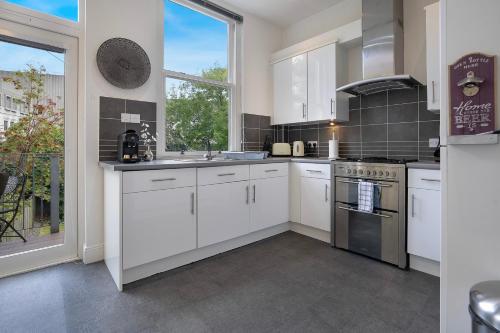 une cuisine avec des placards blancs et une grande fenêtre dans l'établissement Crimon Place Townhouse - Grampian Lettings Ltd, à Aberdeen