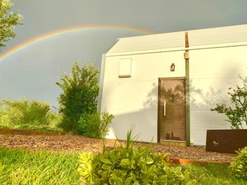 Finca La Escondida San Rafael في سان رافاييل: قوس قزح فوق مبنى أبيض به مرآب