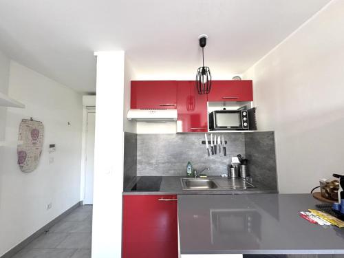 une cuisine avec des armoires rouges et un évier dans l'établissement ApartHotel riviera - Balcon Jean Jaures 2 - Place Massena - Old, à Nice