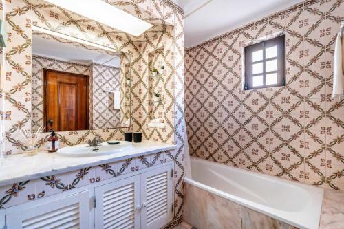 un bagno con un lavandino, una vasca e uno specchio di Casa N's ad Albufeira