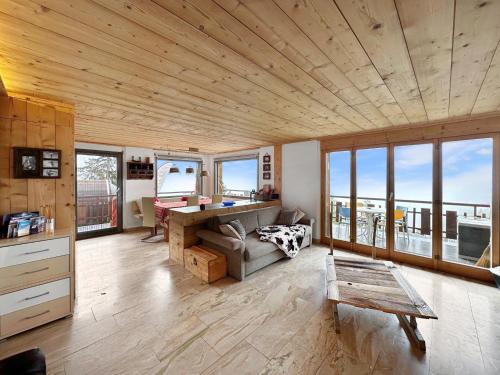 a living room with a couch and a desk and windows at Mountain Bliss, view and Sauna - Swiss Alps in Anzère