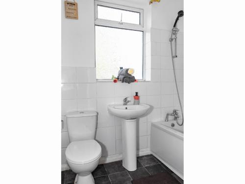 a bathroom with a toilet and a sink and a window at Spacious Pad - Long Stays & Contractors - Close to Sports Village, Leigh Market, & Mesnes Park - Easy Parking - Speedy Wi-Fi in Leigh