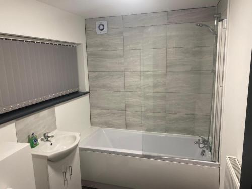 a bathroom with a shower and a tub and a sink at Houghton Guest House in Stoke on Trent