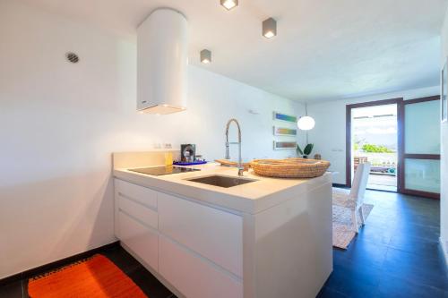 a white kitchen with a sink and a table at Villa Altxor in Stintino