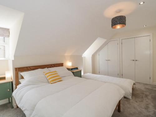 2 camas en un dormitorio con paredes blancas en The Coach House, en Castle Cary