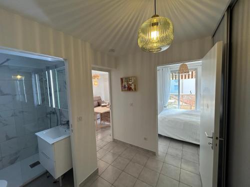 une salle de bain avec un lavabo, un lit et un lustre dans l'établissement Appartement cosy à 200 m de la mer, à Cagnes-sur-Mer