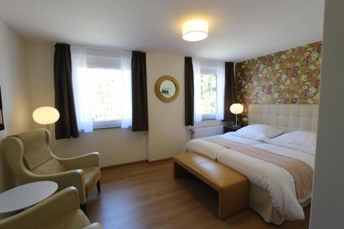 ヘレンタールにあるBoutique Hotel Restaurant Hollerather Hofの大きなベッドと2つの窓がある寝室
