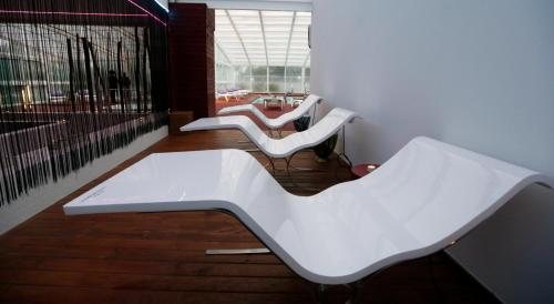 a group of white benches sitting in a room at Hotel Spa Congreso in Teo