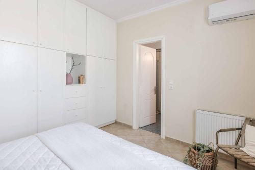 a white bedroom with a bed and a chair at Villa Alba Minies in Minia