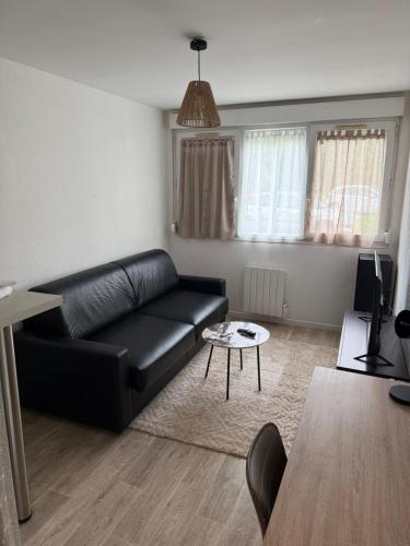 un salon avec un canapé en cuir noir et une table dans l'établissement Studio design et cosy, à Dijon