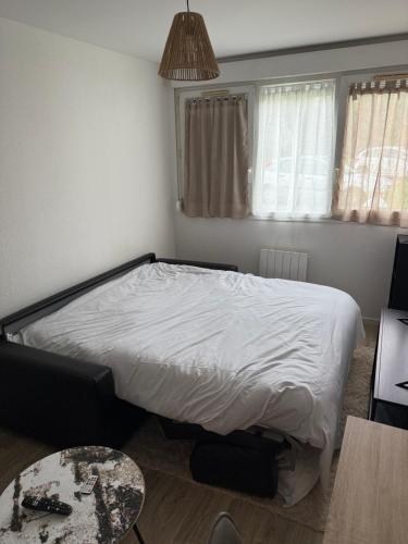 une petite chambre avec un lit et une table dans l'établissement Studio design et cosy, à Dijon