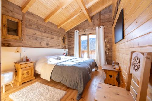 une chambre avec un lit dans une pièce aux murs en bois dans l'établissement Chalet Les Rennes, à Saint-Étienne-de-Tinée