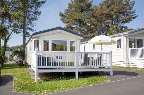a small white house with an umbrella at Seascape at Landscove Holiday Park, Brixham in Brixham