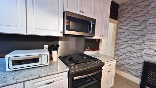 a kitchen with white cabinets and a stove and microwave at Hollywood Glam Themed Manor with Sauna for 12-People in Lancaster