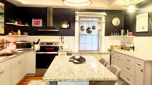 a kitchen with white cabinets and a marble counter top at Hollywood Glam Themed Manor with Sauna for 12-People in Lancaster