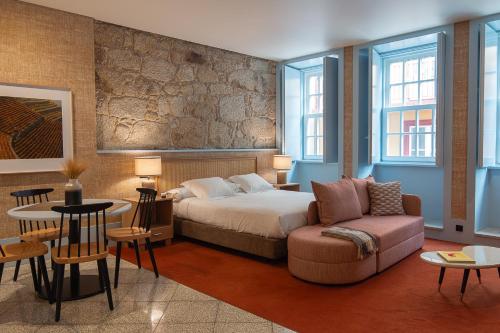 a bedroom with a bed and a couch and a table at Apartamentos The Arc Carrís in Porto