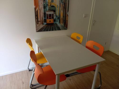 a white table with orange chairs in a room at Hauptstr 10- 04603 Remsa in Windischleuba