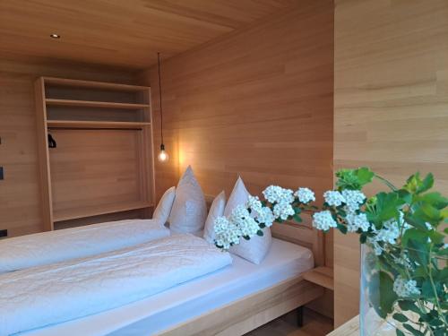a bedroom with a bed with white sheets and a vase of flowers at NEU ausZEIT985 - auszeit mit ausblick in Schwarzenberg