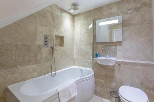 Un baño con bañera, inodoro y lavabo. en Anzac Lookout Central Brixham Retreat with Stunning Views, en Brixham