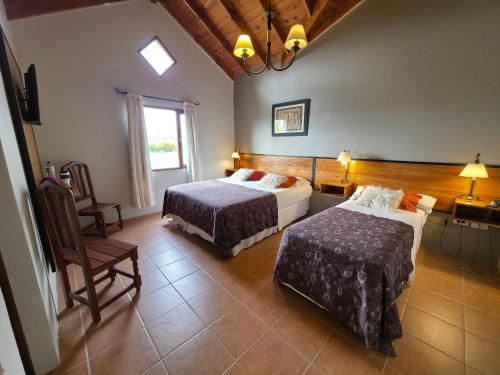 une chambre d'hôtel avec deux lits et une chaise dans l'établissement Glaciares De La Patagonia, à El Calafate