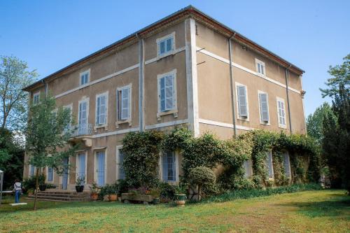 un grand bâtiment avec du lierre sur son côté dans l'établissement Château d 'Olonzac - Maison familiale avec grand jardin, à Olonzac